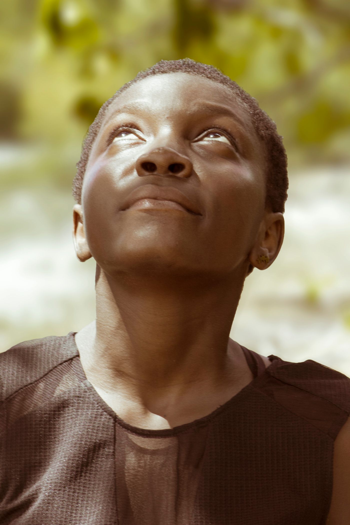 A woman in a calm outdoor setting, looking ahead with quiet resolve